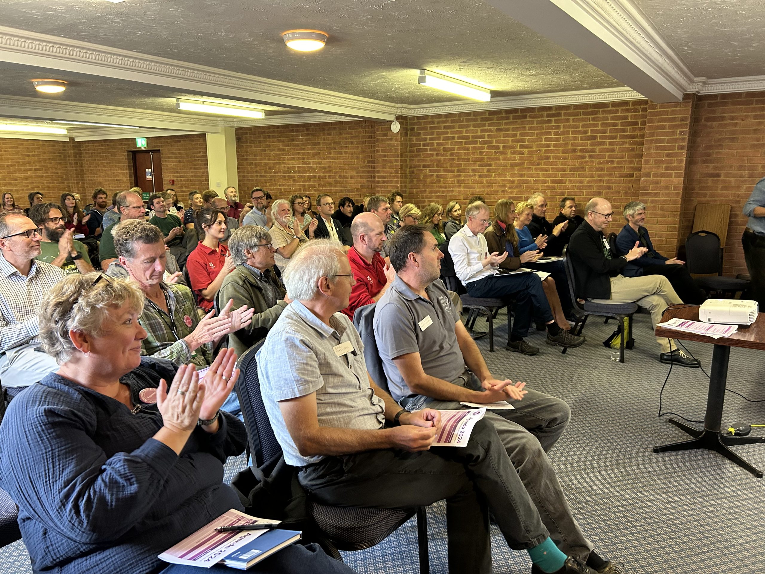 A photo of a room full of people clapping.